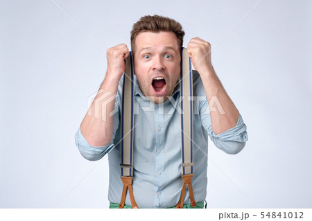 Shocked face of young european man in blue shirt and suspenders Shocked face of young european man in blue shirt and suspenders 54841012