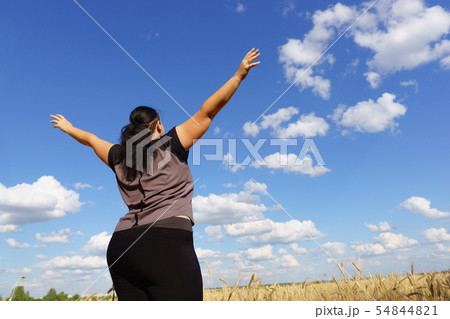 Overweight woman rising hands to the sky Overweight woman rising hands to the sky 54844821
