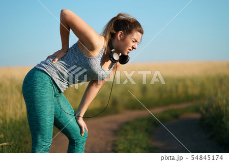 Backache. Woman touching paining small of her back Backache. Woman touching paining small of her back 54845174