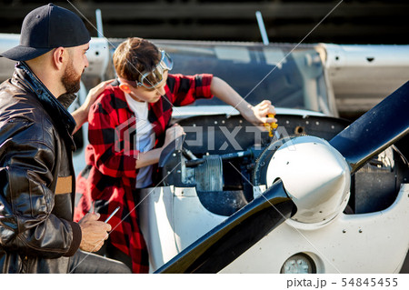 father pats his kid on the back for his progress in fixing works for airplane father pats his kid on the back for his progress in fixing works for airplane 54845455