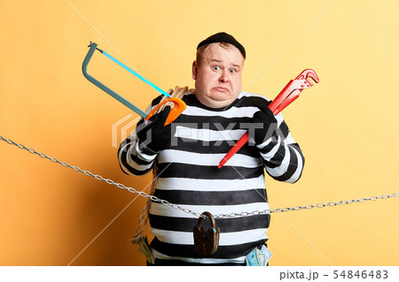 surprised puzzled burglar choosing a tool to cut the chain 54846483
