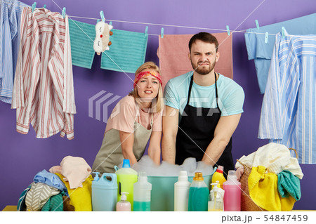 man and woman washing dirty clothes in the bowl with foam 54847459