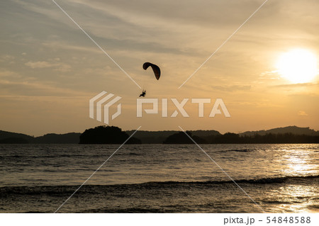 beautiful Silhouette of paraglider flying in the sky of sunset on the beach. beautiful Silhouette of paraglider flying in the sky of sunset on the beach. 54848588