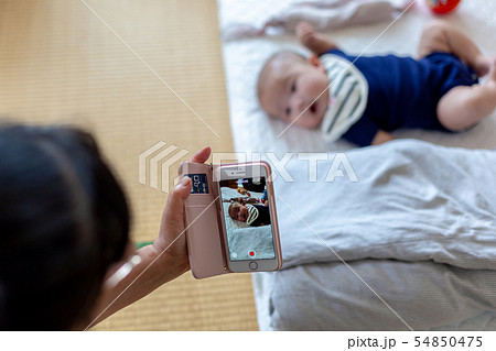 5ヵ月 携帯で赤ちゃんの動画を撮る母親 5ヵ月 携帯で赤ちゃんの動画を撮る母親 54850475