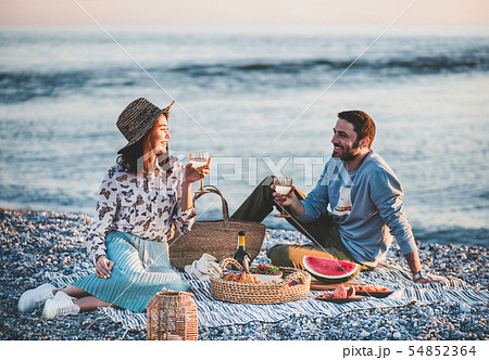 Young couple having picnic at seaside with wine 54852364