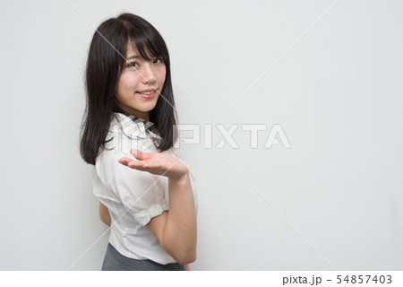 体を横に向けてご案内する女性 54857403