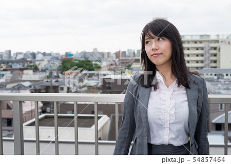 屋上でフェンスに寄りかかる女性の写真素材