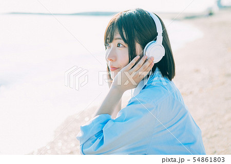 海で音楽を聴く女子高生の写真素材