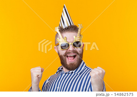 Crazy young positive hipster guy with a beard laughs happily on a yellow background. The concept of 54862575