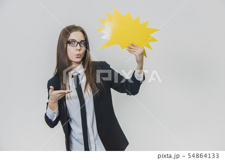 Young woman is holding a yellow speech bubble, which is star-shaped, isolated, on the white Young woman is holding a yellow speech bubble, which is star-shaped, isolated, on the white 54864133