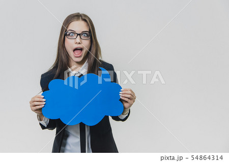 Young woman is holding a blue speech bubble in front of herself, which is cloud-shaped, isolated, on Young woman is holding a blue speech bubble in front of herself, which is cloud-shaped, isolated, on 54864314