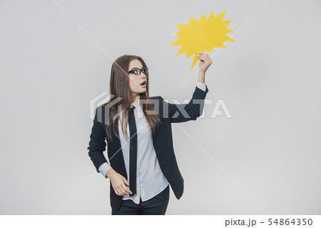Young woman is holding a yellow speech bubble, which is star-shaped, isolated, on the white Young woman is holding a yellow speech bubble, which is star-shaped, isolated, on the white 54864350