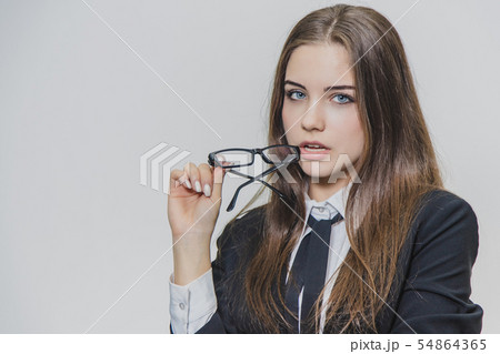 Charming sexy young businesswoman is holding glasses near her slightly open mouth. Girl has her body Charming sexy young businesswoman is holding glasses near her slightly open mouth. Girl has her body 54864365