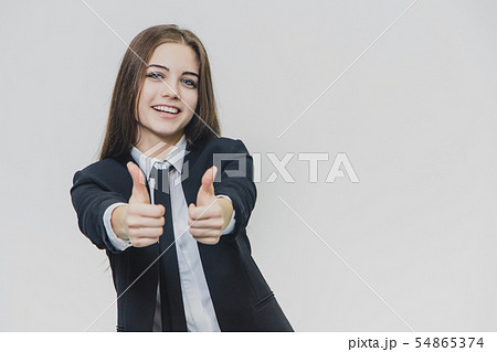 Female hand gestures thumbs up. Business girl is smiling broadly and shares positive emotions. 54865374