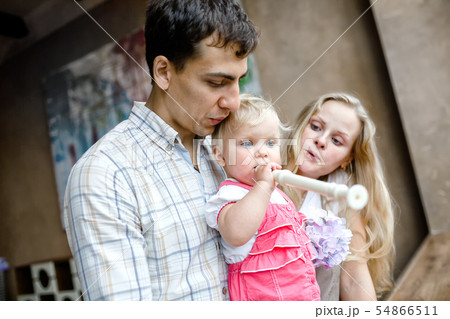 Tender family hugs. Mom, dad and daughter enjoy each other, girl playing a pipe 54866511