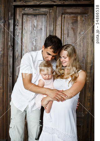 Family portrait. Happy couple holding a little girl. Awesome mom is pregnant 54866538