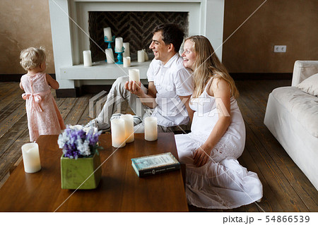 young parents admire their one-year-old daughter, laughing, sitting on the floor 54866539
