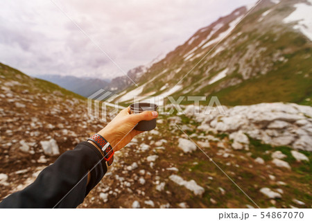 A hand with a mug of clear water against the A hand with a mug of clear water against the 54867070