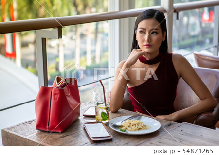 Beautiful young asian woman in red dress sitting 54871265