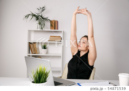 Streatching woman having rest at a workplace. Streatching woman having rest at a workplace. 54871539