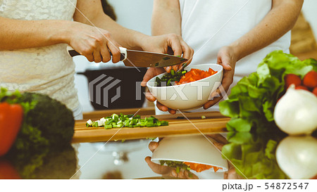 Closeup of human hands cooking in kitchen. Mother and daughter or two female friends cutting 54872547
