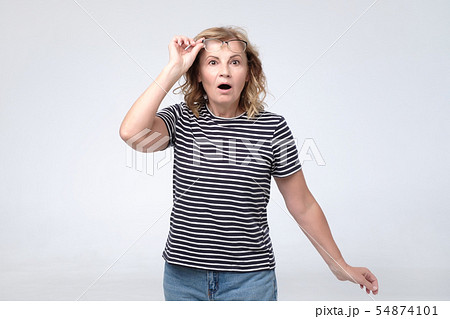 Attractive lovely pretty mature lady opened mouth touching glasses amazed with price. Attractive lovely pretty mature lady opened mouth touching glasses amazed with price. 54874101