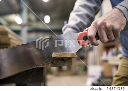 Sawing a wooden board with special japanese hand saw or hacksaw during carpentry 54874386