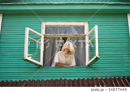 Woman near window looking up facing the sunrise at morning. 54877449