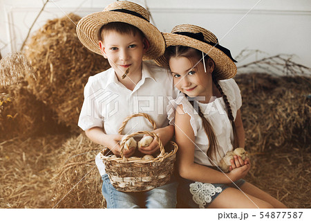 Brother and sister in hay hats keeping little Brother and sister in hay hats keeping little 54877587