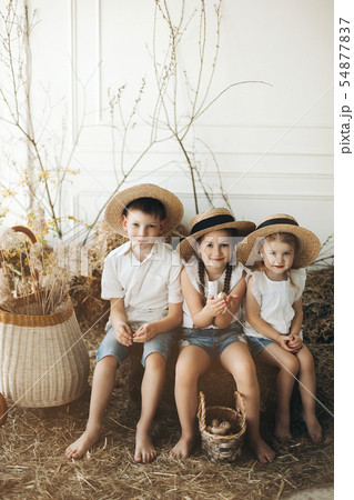 Cute sisters and brother in hay hats resting on 54877837