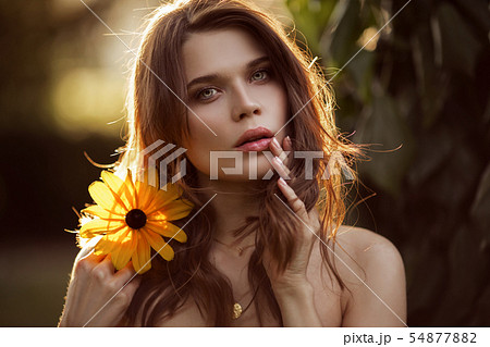 Outdoor fashion photo of beautiful young woman with yellow flower Outdoor fashion photo of beautiful young woman with yellow flower 54877882