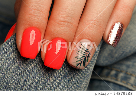 Bright neon red manicure on female hands on the background of jeans. Nail design. Beauty hands. 54879238