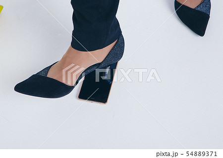 girl puts a foot on the phone. the heel breaks a smartphone. Businesswoman went crazy. Close up on 54889371