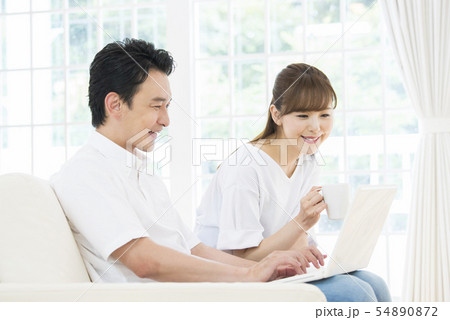 ノートパソコンで検索をする夫婦 54890872