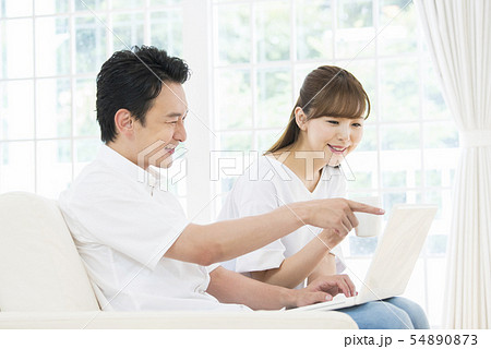 ノートパソコンで検索をする夫婦 54890873