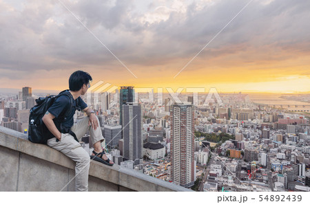 a man with backpack looking at city view in sunset a man with backpack looking at city view in sunset 54892439