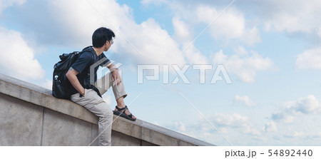 Asian man with backpack looking at blue sky Asian man with backpack looking at blue sky 54892440