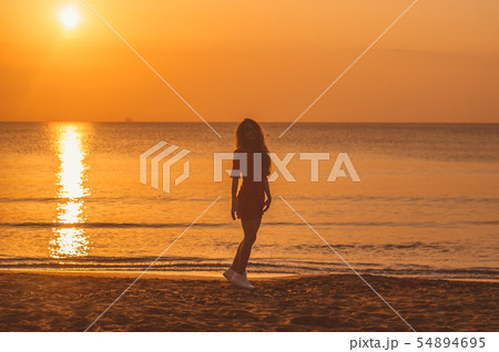 Young blonde girl in red dress jumping 54894695