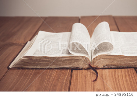 Bible on table with pages folded into heart shape 54895116