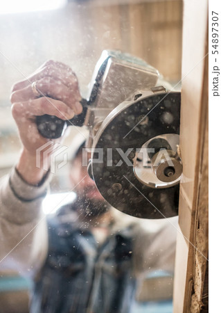 Carpenter using electric woodworking routing a wooden plank 54897307