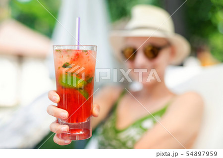 Young beautiful happy woman holding in hand and give glass with fresh cold strawberry non-alcoholic Young beautiful happy woman holding in hand and give glass with fresh cold strawberry non-alcoholic 54897959