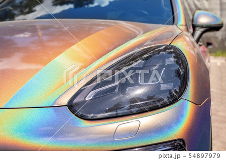 Close-up LED headlight expensive car part with exclusive iridescent painting. Vehicle covered with 54897979