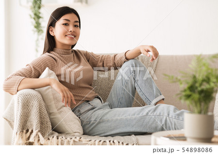 Carefree Teen Girl Looking at Camera, Resting on Sofa Carefree Teen Girl Looking at Camera, Resting on Sofa 54898086