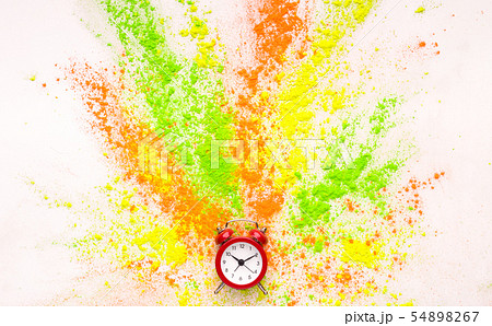 Coloured holi powder explosion out of alarm clock on white 54898267