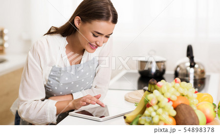 Millennial woman searching recipe on tablet, cooking dinner Millennial woman searching recipe on tablet, cooking dinner 54898378