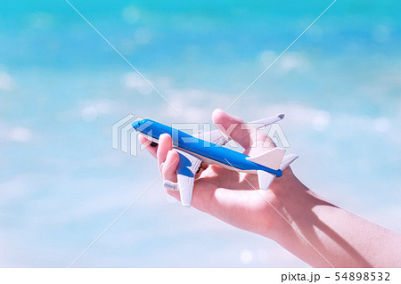 Hand with a toy aircraft against blue water and 54898532