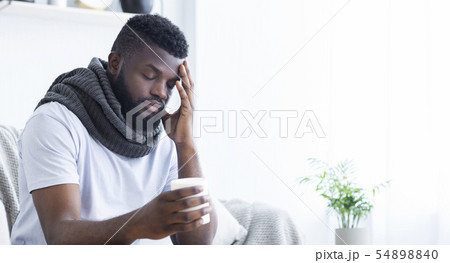 Sad african-american man with flu holding cup with hot tea 54898840