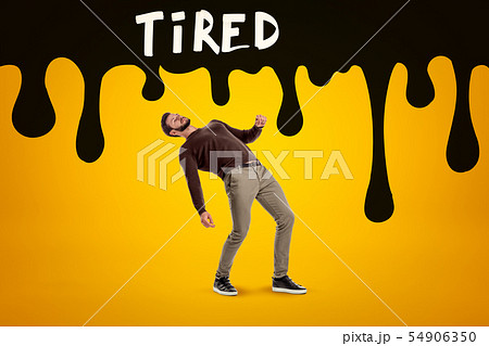 Young man in casual clothes falling with black TIRED sign above on yellow background Young man in casual clothes falling with black TIRED sign above on yellow background 54906350