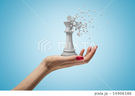 Closeup of woman's hand facing up and holding big white chess king that has started to dissolve into 54906386