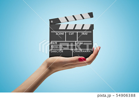 Side closeup of woman's hand facing up and holding clapperboard on light-blue gradient background. 54906388